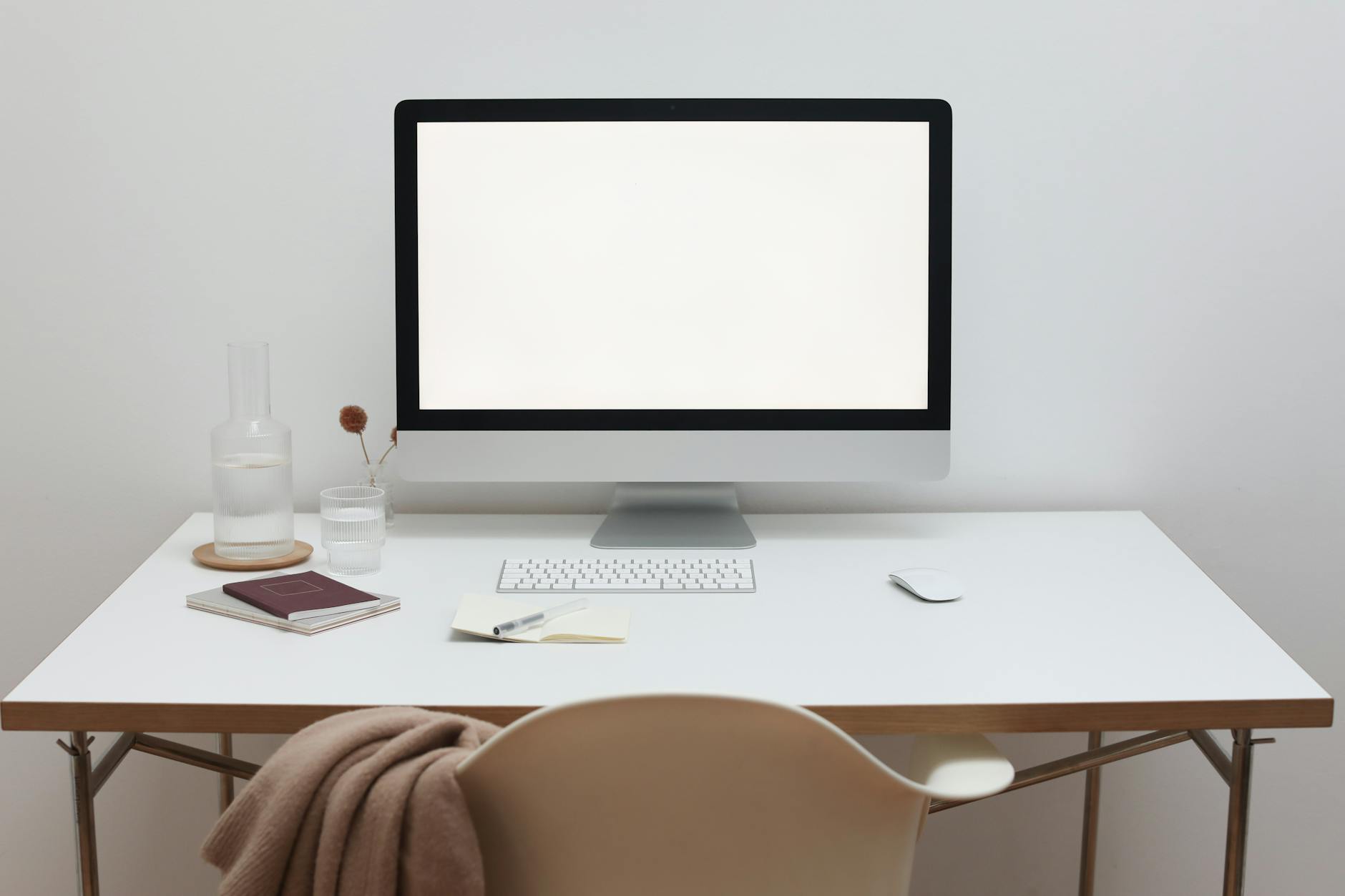 Modern minimalist home office setup with blank screen, keyboard, and stylish decor on a sleek desk.